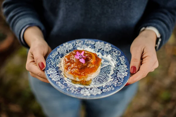 Mujer sosteniendo un plato azul adornado con una deliciosa mermelada de naranja en el pan — Foto de Stock