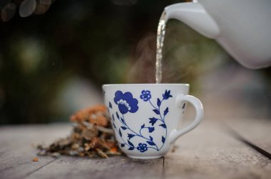 Çay beyaz bir çaydanlık Mavi desenli cam içine dökülür