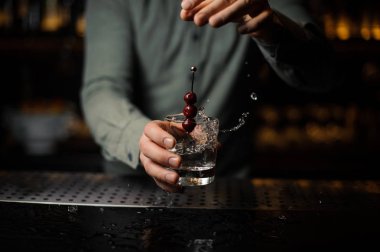 Barmen bir kokteyl bardağına bir çilek bir şiş üzerinde atma