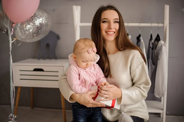 Donna sorridente e la sua piccola figlia carina in possesso di un regalo — Foto Stock