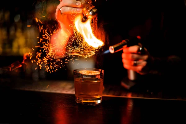 Bartender adding to a cocktail brown spice and flame it — Stock Photo, Image