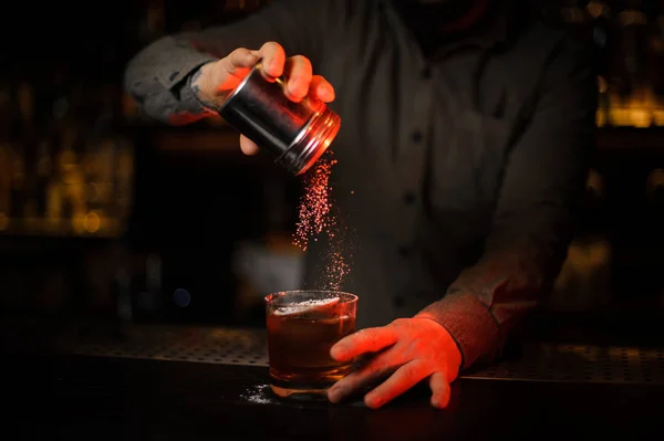 Cantinero añadiendo a una especia de cóctel de una coctelera de acero — Foto de Stock