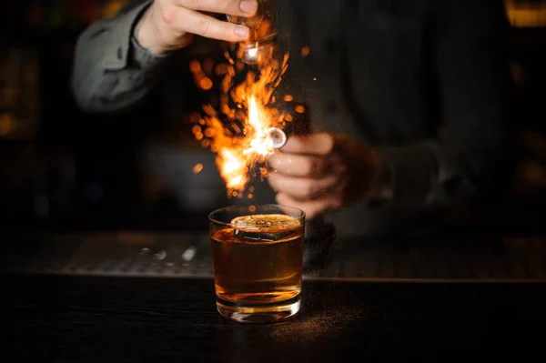 Bartender adding to a cocktail brown spice and flaming it — Stock Photo, Image