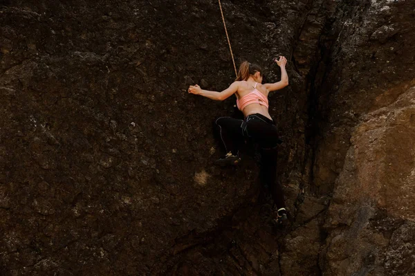 Woman equipped with a rope climbing on the rock