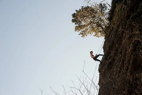 Deportiva mujer equipada con una cuerda rappel en la roca inclinada — Foto de Stock