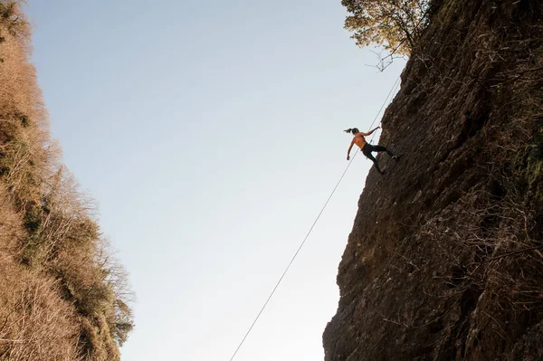 Mujer fuerte equipada con una cuerda rappel en la roca inclinada — Foto de Stock