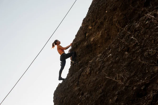 Chica equipada con una cuerda trepando en la roca inclinada — Foto de Stock