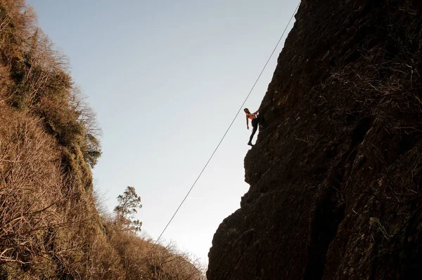 傾斜した岩の上を登ると振り返ってロープ装備の女の子 — ストック写真