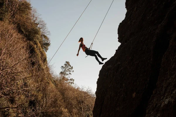 Slim fit meisje uitgerust met een touw abseilen op de hellende rots — Stockfoto