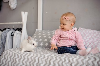 Beyaz tavşan ile oynayan sevimli küçük kız