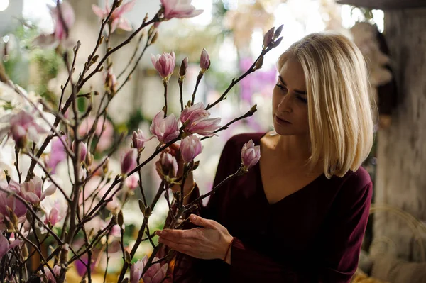 Блондинка стоїть серед квітучих квітів магнолії — стокове фото