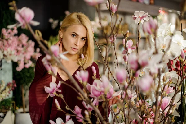 Mujer rubia de pie entre flores florecientes magnolia — Foto de Stock