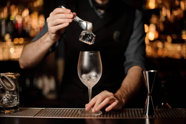 Barman ajoutant à un verre à cocktail un gros glaçon — Photo