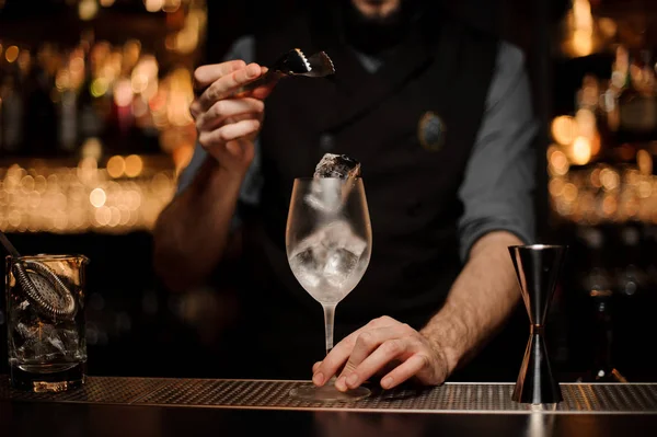 Barman jogando a uma taça de coquetel um grande cubo de gelo — Fotografia de Stock