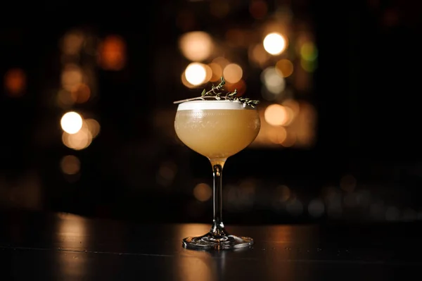 Вкусный желтый коктейль в стакане украшен копченой травой — стоковое фото