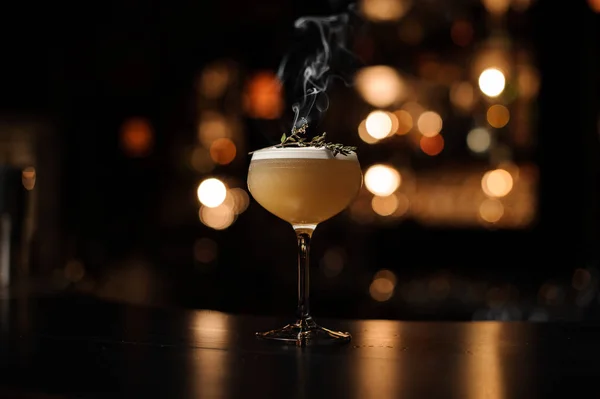 Delizioso cocktail con una schiuma nel bicchiere decorato con un'erba affumicata — Foto Stock
