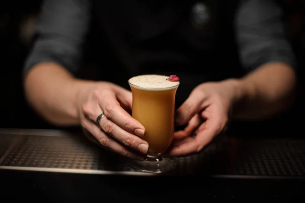 Barman professionnel servant un cocktail dans le verre avec de la mousse décorée d'un bouton de rose rouge — Photo