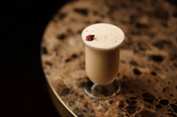 Blick von oben auf den köstlichen Cocktail im Glas mit einer einzigen roten Rosenknospe, die auf dem Tisch steht — Stockfoto