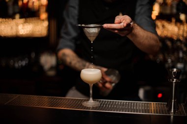 Profesyonel barmen lezzetli bir kokteyl elek ile dökme