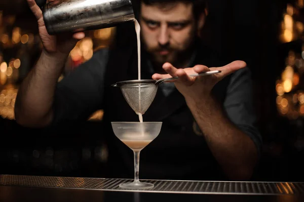 Barista versare cocktail dallo shaker attraverso il colino — Foto Stock