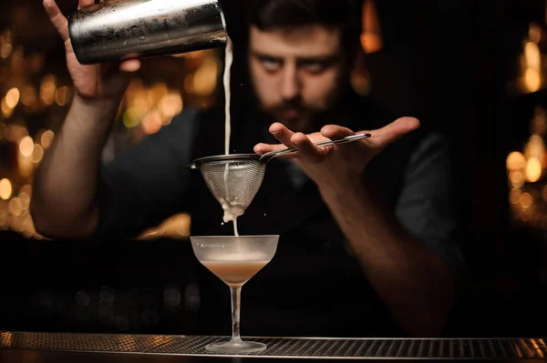 Brunett bartendern hälla cocktail från shakern genom Silen — Stockfoto