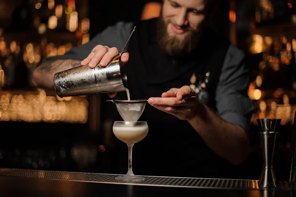 Profesionální barman nalil lahodný koktejl z oceli třepačce přes sítko — Stock fotografie