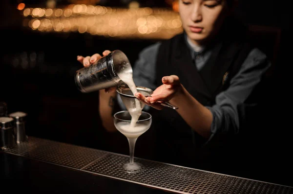 Professionele barman meisje een heerlijke cocktail van de stalen shaker door de zeef gieten — Stockfoto