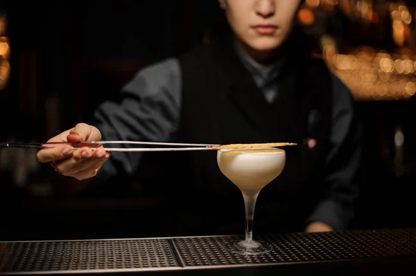 Professionele barman meisje toe te voegen aan een heerlijke cocktail gedroogde decor met een pincet — Stockfoto
