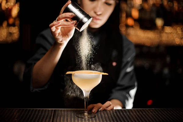 Chica camarera profesional sosteniendo una coctelera de especias añadiendo a un delicioso cóctel sabores — Foto de Stock