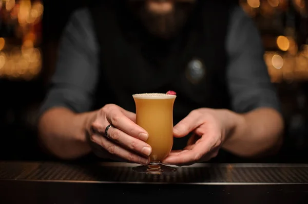 Männlicher Barkeeper serviert einen Cocktail im Glas mit Schaumstoff, der mit einer einzigen roten Rosenknospe verziert ist — Stockfoto