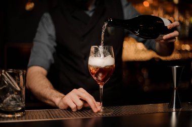 Barmen bir bar kokteylde köpüklü şarap ekler sayaç
