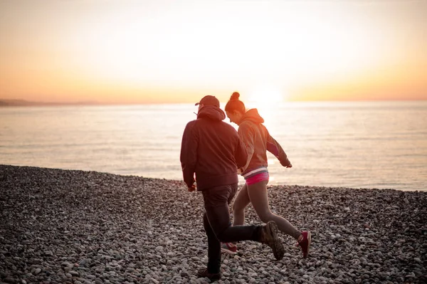Молода романтична пара біжить на пляжі тримаючись за руки — стокове фото