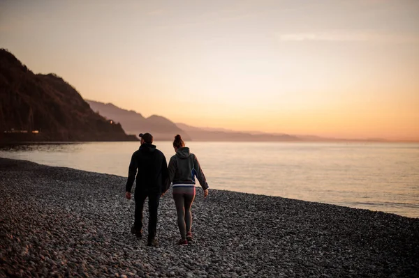 Unga romantiska par promenader på stranden håller händerna — Stockfoto