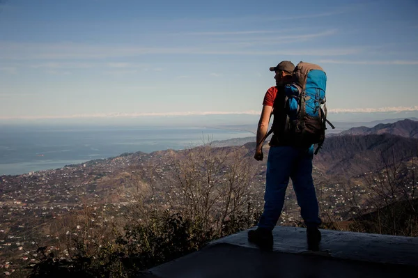 Hombre con una mochila de pie y mirando a las montañas —  Fotos de Stock