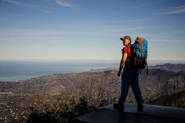 Hombre fuerte con una mochila de pie y mirando a las montañas —  Fotos de Stock