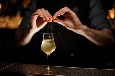 Barmen cam lezzetli şeffaf sarı kokteyl üzerinde bir limon suyu ile püskürtme