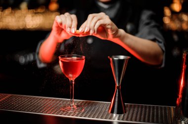 Profesyonel barmen kız lezzetli bir kırmızı kokteyl bir limon Zest ekleyerek