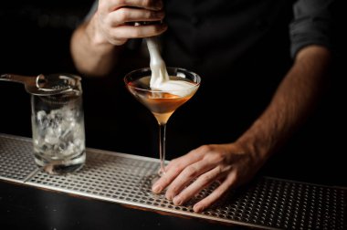 Profesyonel barmen cam bir kokteyl bir krema ekleyerek