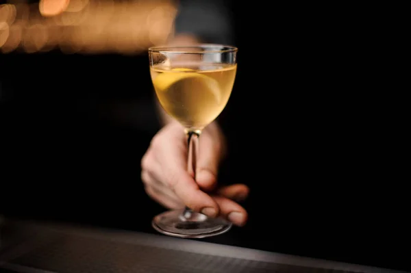 Bartender menyajikan koktail kuning transparan di kaca dihiasi dengan lemon zest di meja baja — Stok Foto