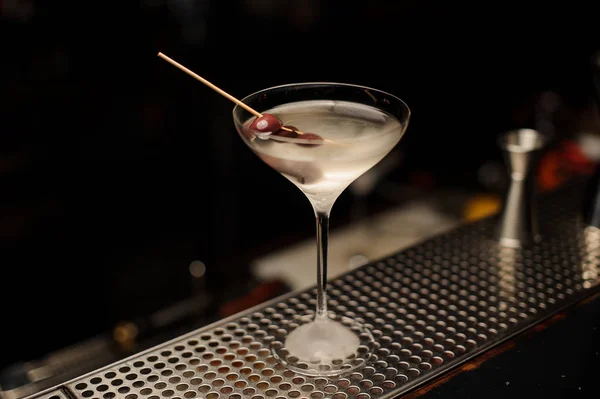 Cocktail nel bicchiere di ghiaccio freddo decorato con bacche sullo spiedo sul bancone del bar — Foto Stock