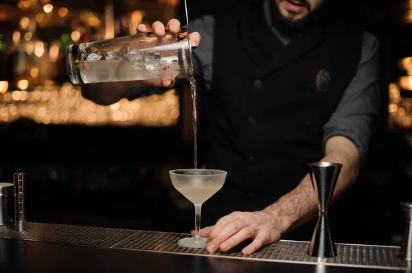 Mannelijke barman gieten een heerlijke cocktail van de maatbeker glas door de zeef — Stockfoto