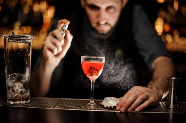 Бармен распыление на вкусный прозрачный красный коктейль в стекле — стоковое фото