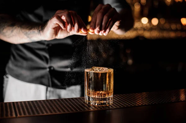 Profesionální barman přidávám koktejl do skleničky citronovou zestu — Stock fotografie