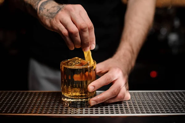 Barman ajoutant à un cocktail dans le verre un zeste de citron comme décor — Photo