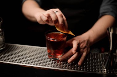 Barmen cam bir kokteyl bir dekor olarak portakal Zest ekleyerek