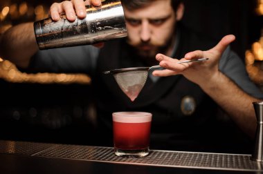 Barmen cam için elek aracılığıyla pürüzsüz bir pembe kokteyl dökme