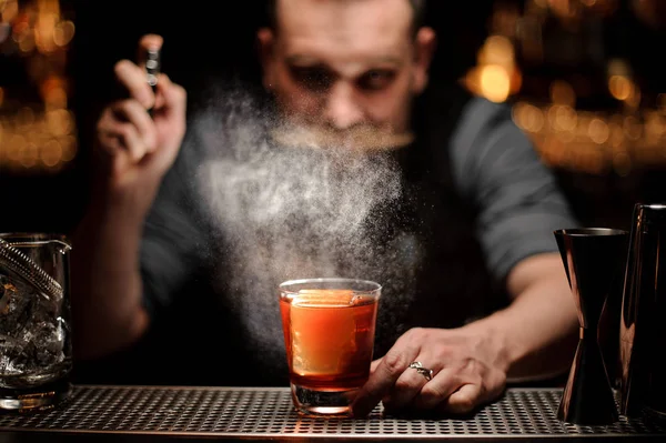 Barman spuiten om de cocktailglas met een grote Ice Cube onder het licht — Stockfoto