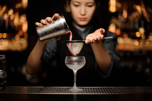 Barkeeperin gießt einen glatten rosa Cocktail durch das Sieb ins Glas — Stockfoto
