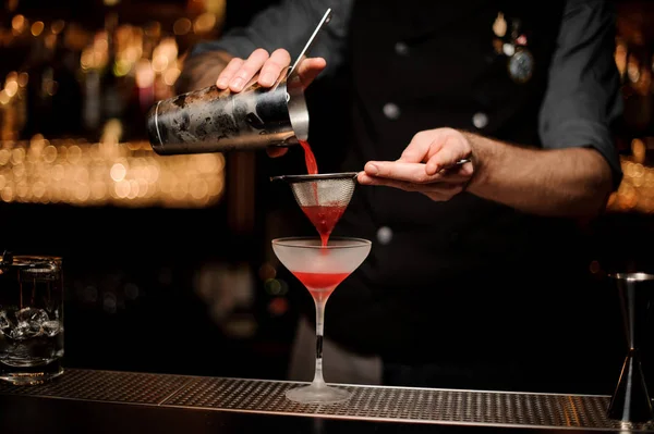 Professionell bartender hälla en slät Crimson cocktail genom sikten till glaset — Stockfoto