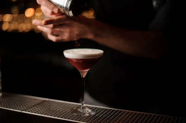 Профессиональный бармен добавляет к коктейлю взбитые сливки красный порошок — стоковое фото
